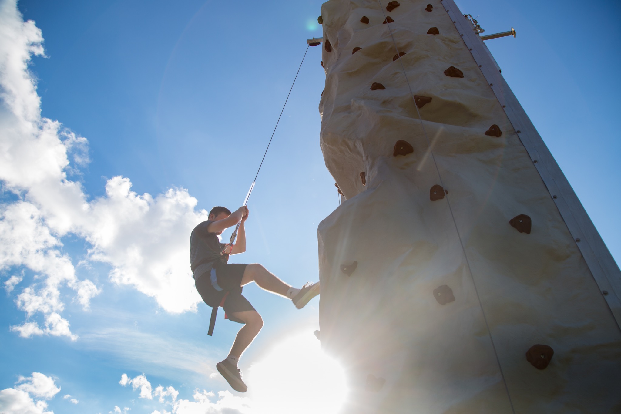 Artificial rock climbing tower, with person descending via rope
