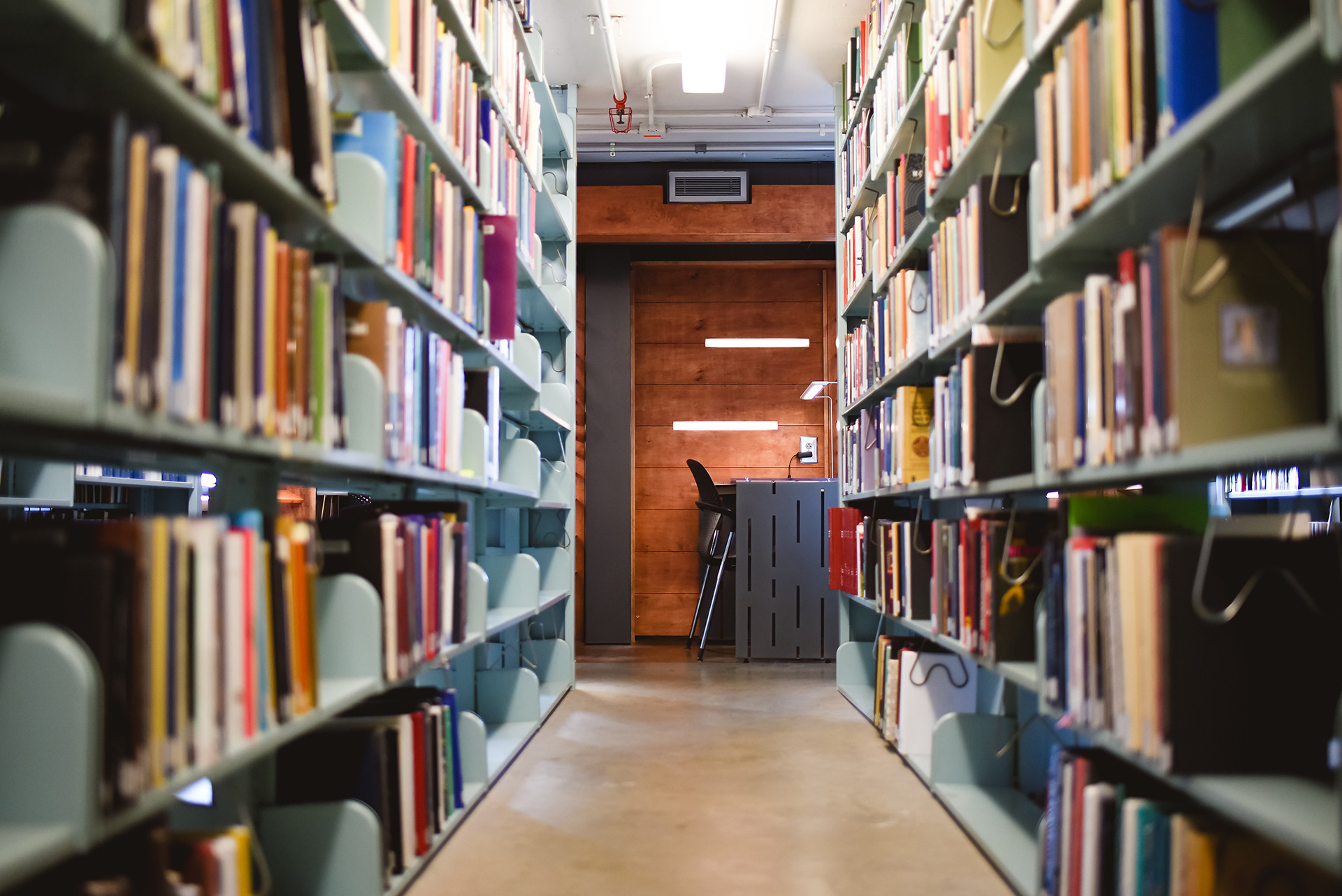 Walkway between two rows of bookshelves, with study carrel in background