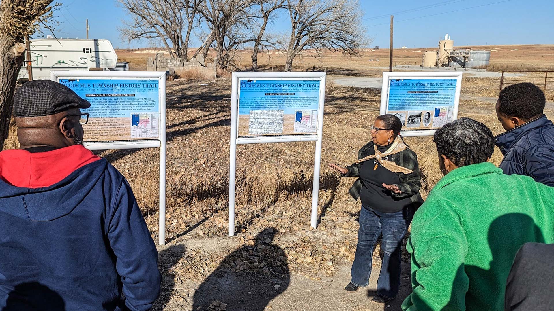 A tour guide gives a presentation near the Nicodemus Trail signs.